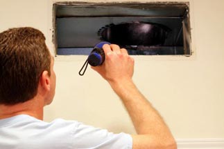 HVAC Technician examining an air duct — Air Conditioning Services in Dumfries, VA